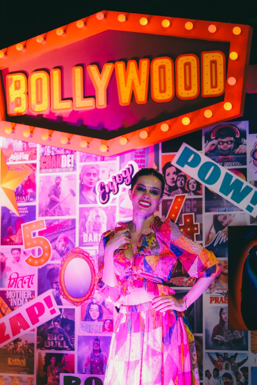 smiling woman standing by wall with bollywood sign